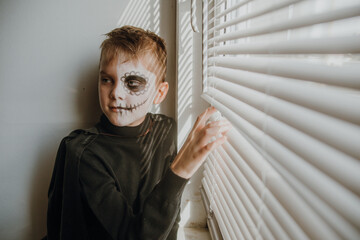 Scary boy celebrating halloweenday of the dead terrifying skull face makeup for eyes mouth