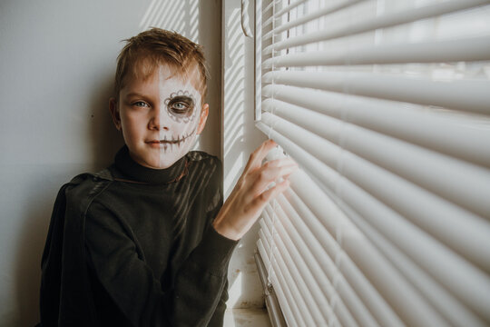 Scary boy celebrating halloweenday of the dead terrifying skull face makeup for eyes mouth