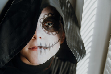 Scary boy celebrating halloweenday of the dead terrifying skull face makeup for eyes mouth