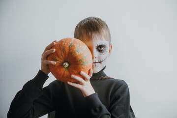Scary boy holds pumpkins for halloween celebration