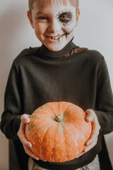 Scary boy holds pumpkins for halloween celebration
