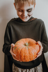 Scary boy holds pumpkins for halloween celebration