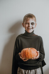 Scary boy holds pumpkins for halloween celebration