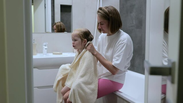 Young mother wipes her daughter after a shower