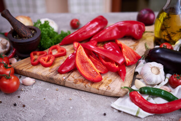red pepper on wooden cutting board and vegetables at domestic kitchen