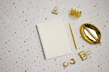 White notebook with golden pen, and leave on glitter background. 