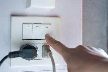 Closeup hand turn off the electricity switch, save power and energy home and routine concept copy space for text and design
