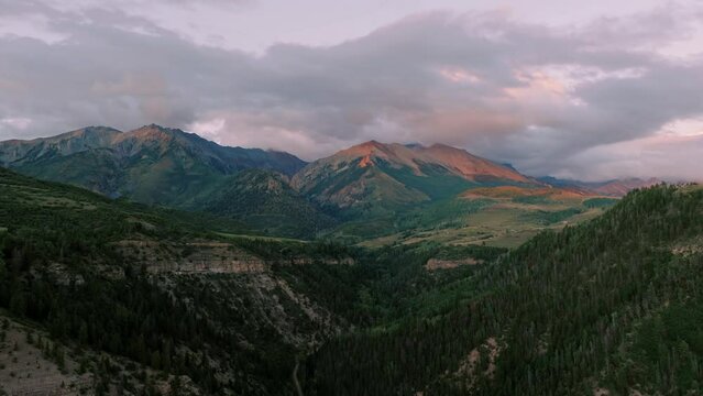 Sunset drone flight of Mears Peak with pink hued clouds near Telluride, Colorado.