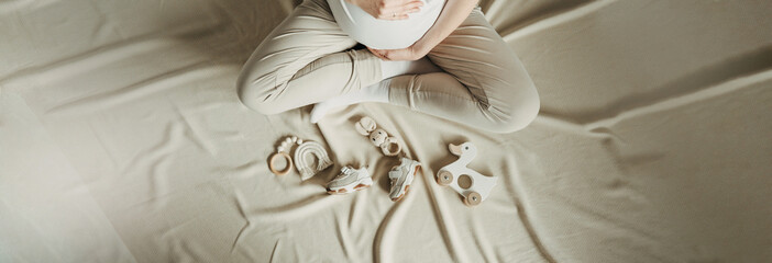 Pregnant woman enjoying future motherhood, preparing to child birth during pregnancy. Mother with wooden stuff for baby. Local eco children products, baby shower. Top view, copy space