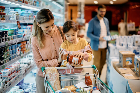 Small Girl And Her Mother Shopping Groceries In Supermarket.