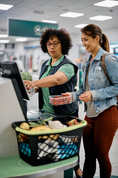 Supermarket Worker Assists Buyer In Using Self-service Till At Checkout.