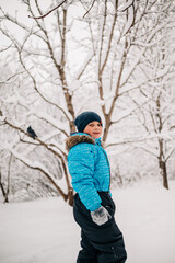 Kid boy in the park at winter snowy outdoors. Wintertime fun