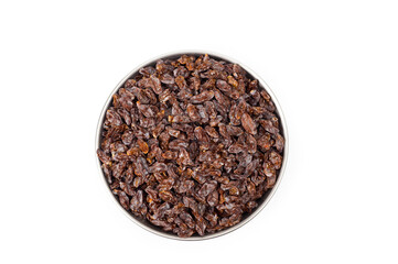 Dark-colored raisins lying in a metal container, shot on a white background.
