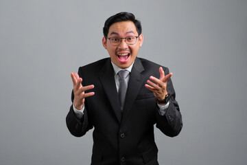 Portrait of excited handsome young businessman in formal suit celebrating success isolated on grey background