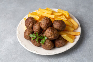 Round shaped balls of dry meatballs and french fries. Turkish name; kuru kofte ve patates