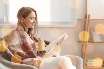 Beautiful woman with cup of tea reading book at home