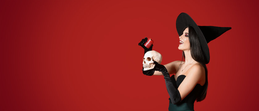 Young witch holding skull and candle on red background with space for text