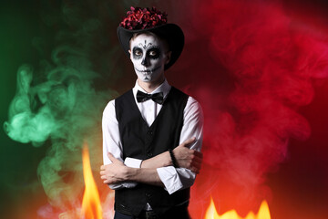 Young man with painted skull on his face for Mexico's Day of the Dead (El Dia de Muertos) against dark color background
