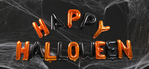 Text HAPPY HALLOWEEN made of balloons and spiderweb on black background