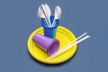 Plastic cutlery and disposable tableware on a gray background. Studio shot, close-up.