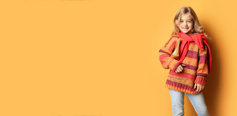 Cute fashionable girl in stylish sweater on orange background with space for text