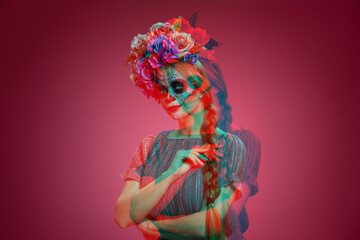 Young woman with painted skull on her face for Mexico's Day of the Dead (El Dia de Muertos) against red background