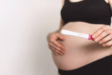 Pregnant woman showing positive pregnancy test on white background. Copy space