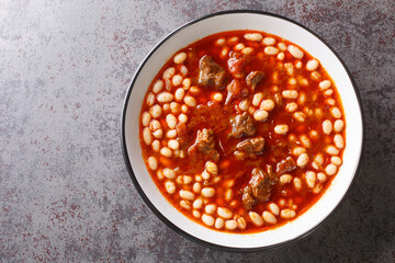 Stew spicy Kuru Fasulye from beans with lamb in tomato sauce close-up in a bowl on the table....