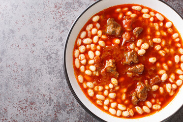 Spicy Turkish food Kuru Fasulye from beans with lamb in tomato sauce close-up in a bowl on the table. horizontal top view from above
