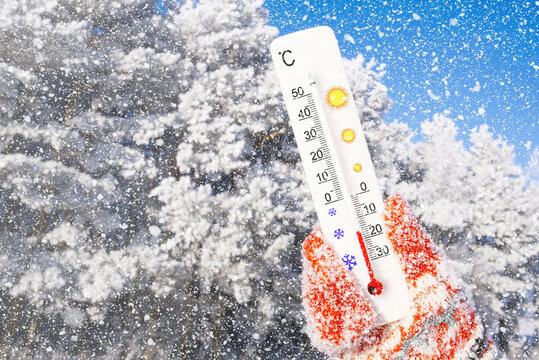Winter holidays with snow. White celsius scale thermometer in hand. Ambient temperature minus 16 degrees celsius