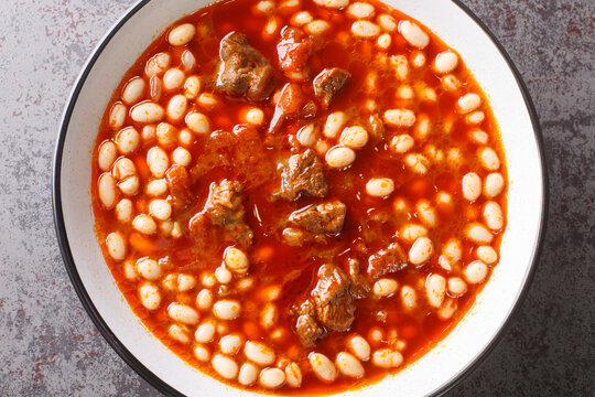 Turkish white bean stew with meat Etli kuru fasulye closeup in the plate on the table. Horizontal top view from above