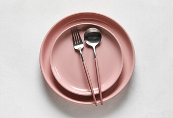 Plates, spoon and fork on white background
