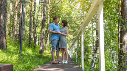 Fototapeta na wymiar An adult couple in love, a man and a woman, are standing on a bridge in the park.