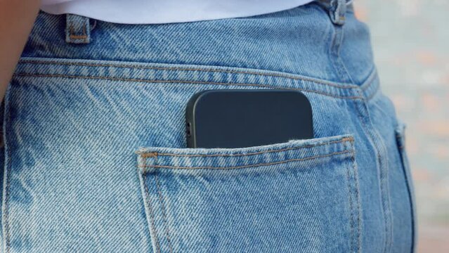 Hand, phone and jeans with a woman putting her mobile in her jeans pockets outside. Cellphone, fashion and communication with a female placing her smartphone in the back pocket of her pants outdoor