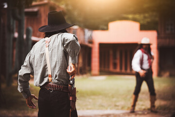 Backside view of cowboy while standing gun prepares on gunfight in cowboys village is cowboy...
