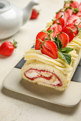 Plate of tasty roll cake with fresh strawberry on light background, closeup