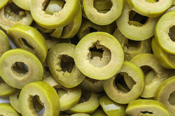 Slices of tasty cut green olives as background, closeup
