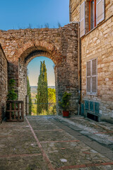 Obraz premium An arch in the ancient walls of Todi, Perugia, Italy, with a cypress in the background