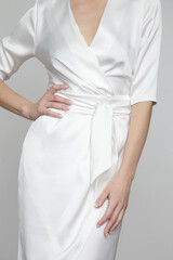 Serie of studio photos of attractive young woman wearing elegant white silk satin dress.