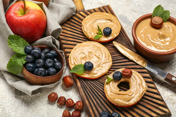 Wooden board of tasty apple rounds with nut butter and blueberry on light background, closeup