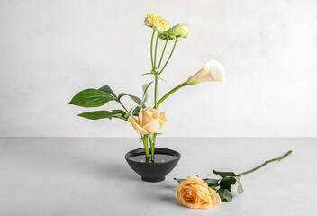Bowl with beautiful ikebana on light background