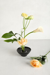 Bowl with beautiful ikebana on light background