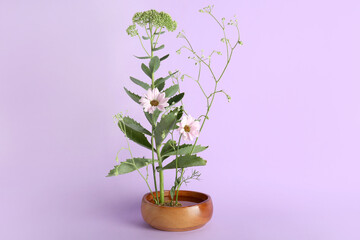 Bowl with beautiful ikebana on lilac background