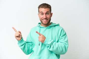 Young handsome caucasian man isolated on white background frightened and pointing to the side