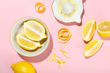 Composition with fresh lemons, peel and juice on pink background