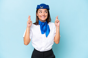 Airplane stewardess caucasian woman isolated on blue background with fingers crossing