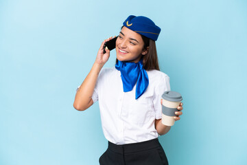 Airplane stewardess caucasian woman isolated on blue background holding coffee to take away and a mobile