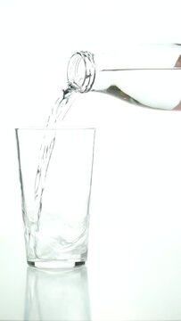 Detail of an unrecognizable man's hand pouring water into a crystal glass on a white background.