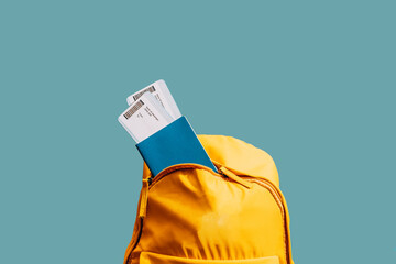 Two tickets in passport from backpack against blue background.