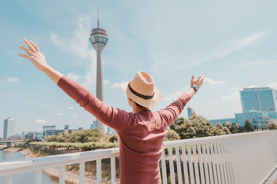 A young happy man at the Media Harbor admiring view of TV-tower in Dusseldorf. Travel abroad and tourist destinations